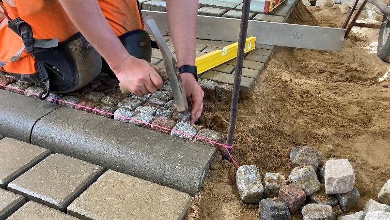 Straßenbauerhandwerk Straßenbauer beim Setzen von Naturpflastersteinen